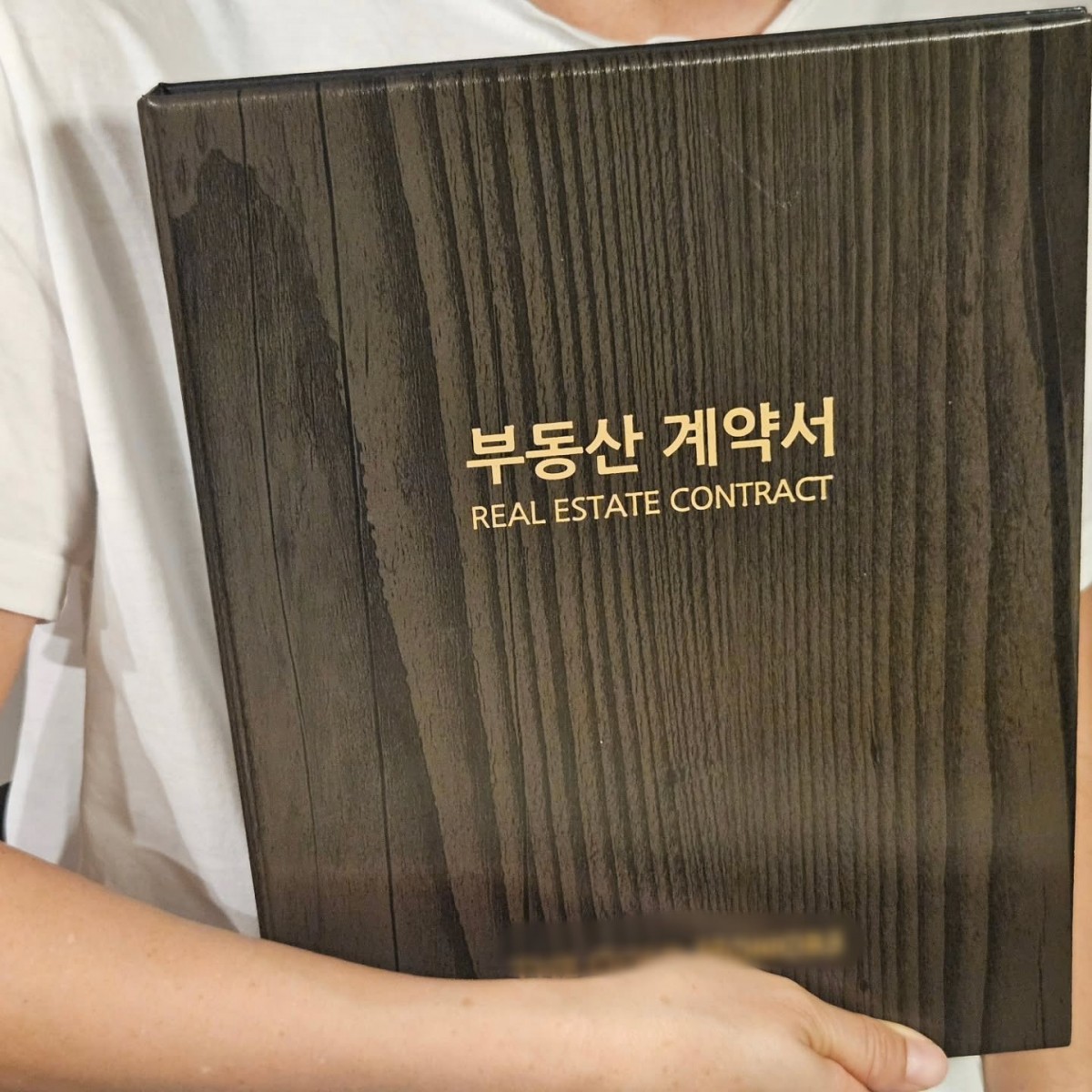 아나운서 출신 방송인 장성규는 그의 아내로 추정되는 인물이 '부동산 계약서'라는 글자가 크게 적힌 계약서 케이스를 품에 안고 있는 모습을 SNS에서 공개했다. / 장성규 인스타그램
