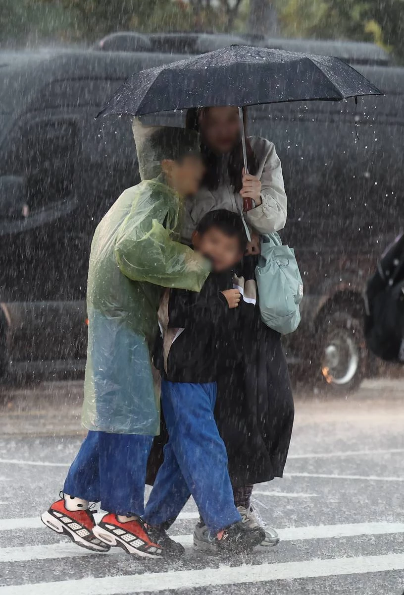 비가 내린 18일 오후 서울 종로구 경복궁 인근에서 한 가족이 우산을 쓰고 이동하고 있다 / 뉴스1