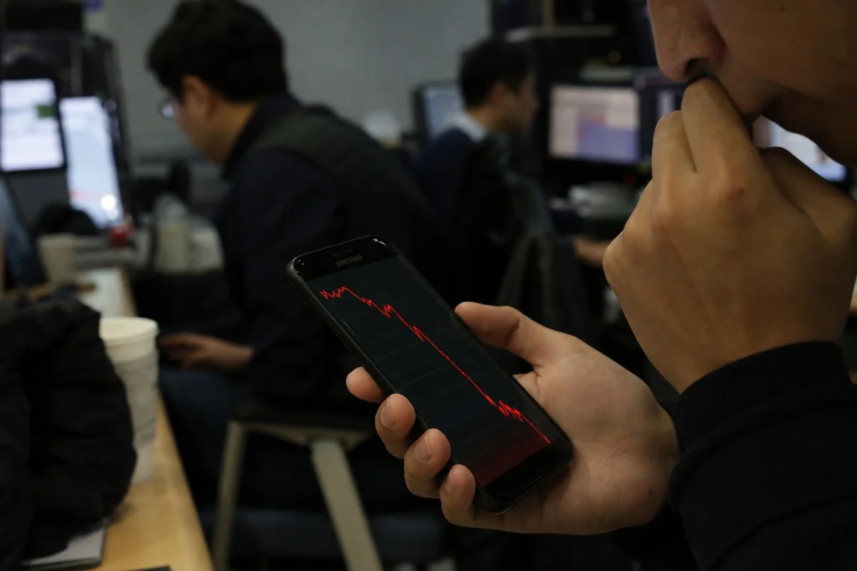 사무실에서 하락 그래프가 표시된 스마트폰을 바라보는 모습 — AI 자료 이미지