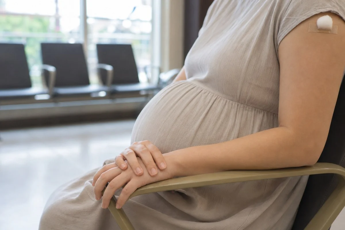 팔에 작은 밴드를 붙인 임신부가 대기 의자에 앉아 있는 모습 — AI로 생성한 자료 이미지