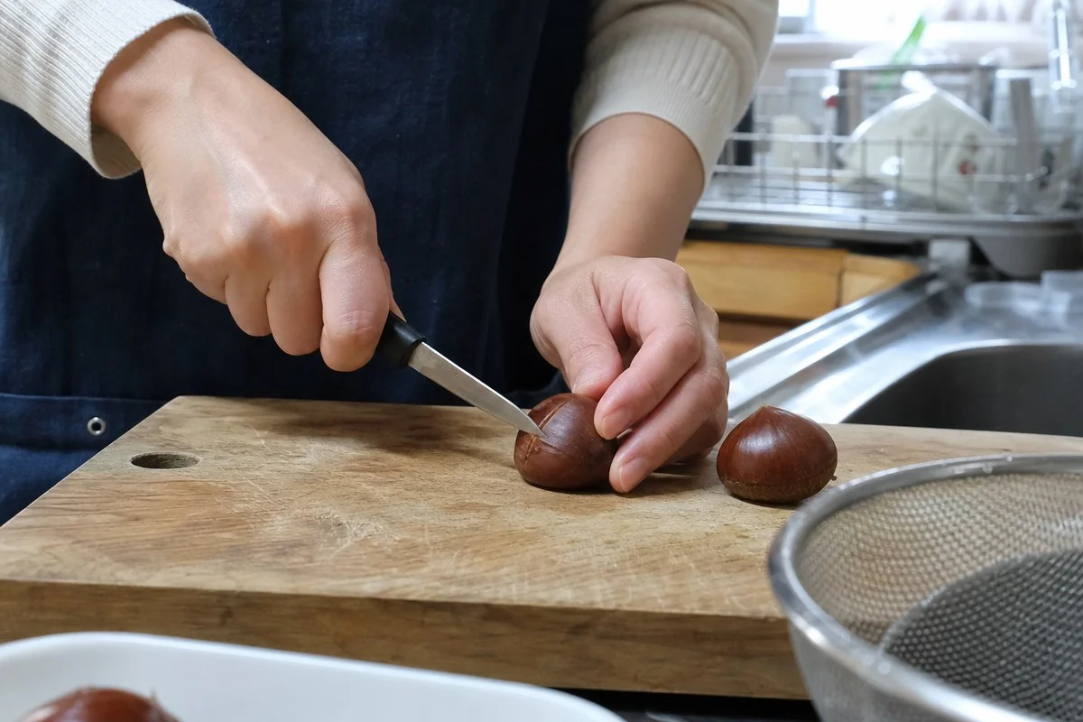 나무 도마 위 생밤 껍질에 칼로 칼집을 내는 모습 — AI로 생성한 자료 이미지