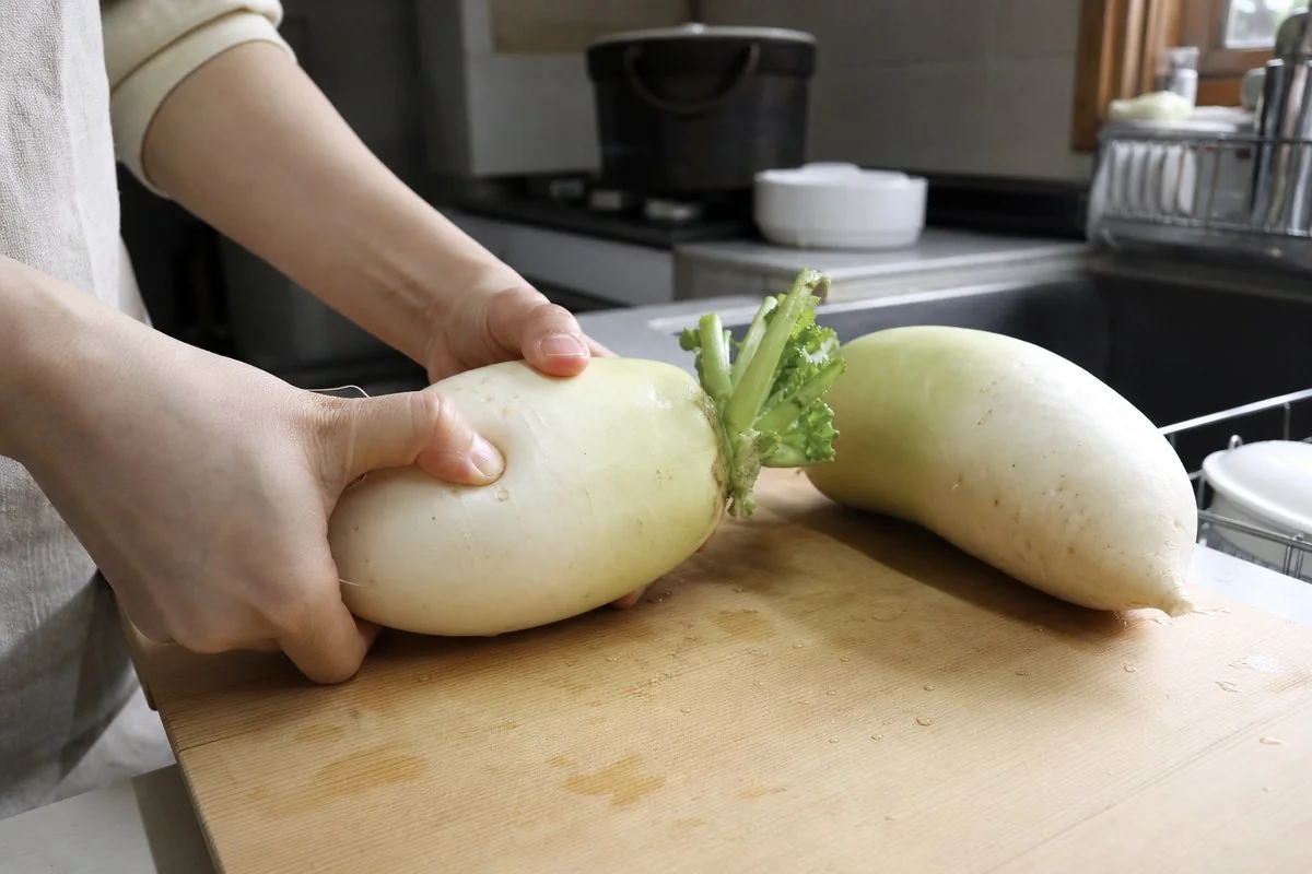 주방 도마 위 무를 손끝으로 눌러보는 모습 — 이해를 돕는 AI 자료 이미지