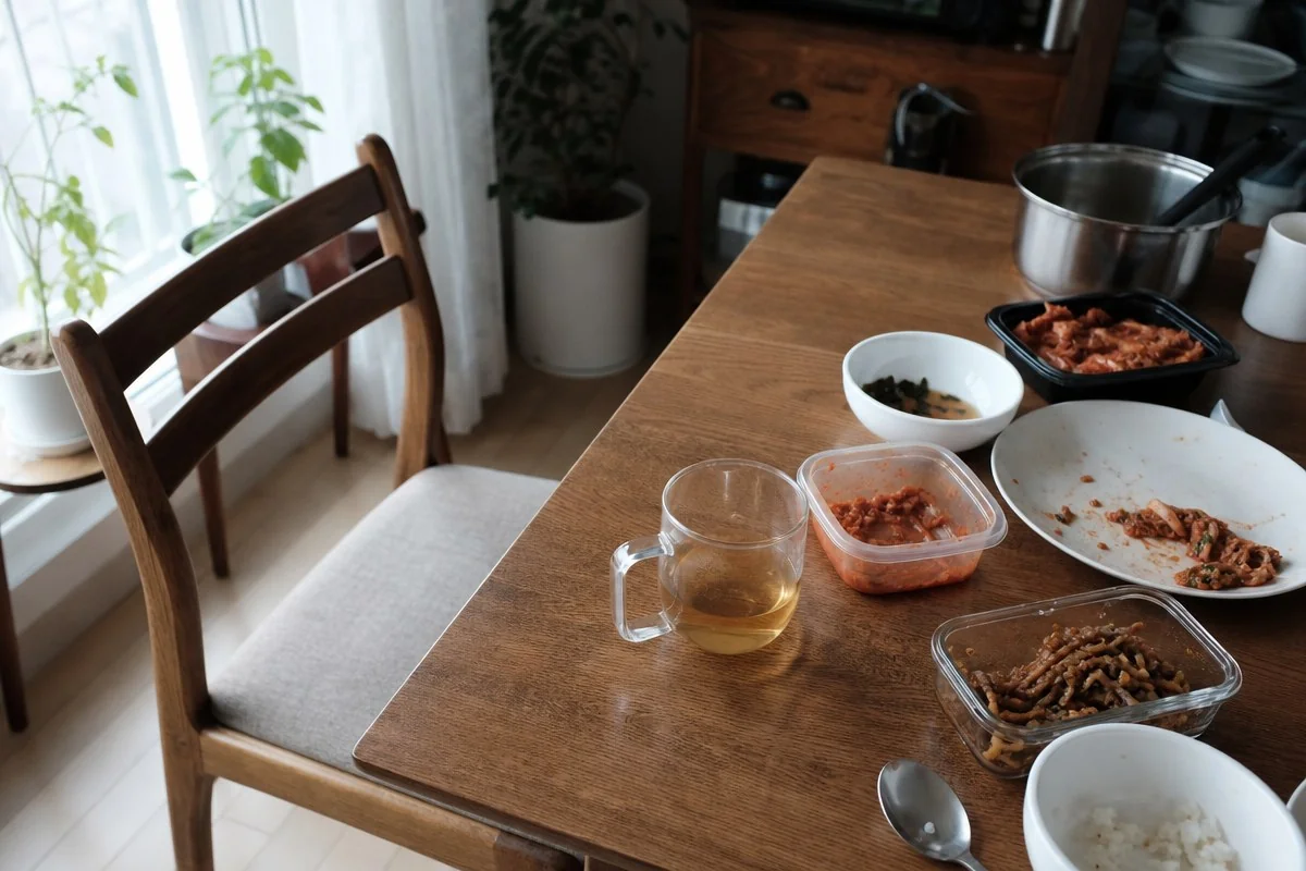 나무 식탁 위에 차와 남은 음식이 담긴 그릇들이 놓인 모습 — AI로 생성한 자료 이미지